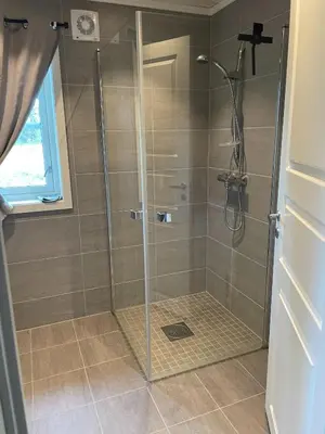 a shower with a glass door in a bathroom at Bjørkefinken by Norgesbooking - cabin for hiking and skiing in Tisleidalen