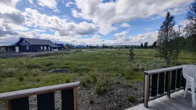 a deck with a chair and a house in a field at Bjørkefinken by Norgesbooking - cabin for hiking and skiing in Tisleidalen
