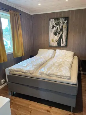 a bed in a bedroom with a painting on the wall at Bjørkefinken by Norgesbooking - cabin for hiking and skiing in Tisleidalen