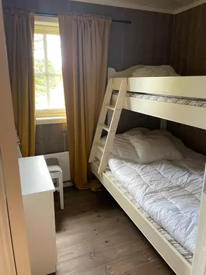 a bedroom with two bunk beds and a window at Bjørkefinken by Norgesbooking - cabin for hiking and skiing in Tisleidalen