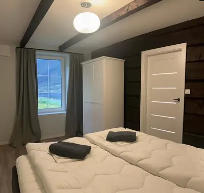 a bedroom with two beds and a window at Husslåttene apartments with terrace in Skei