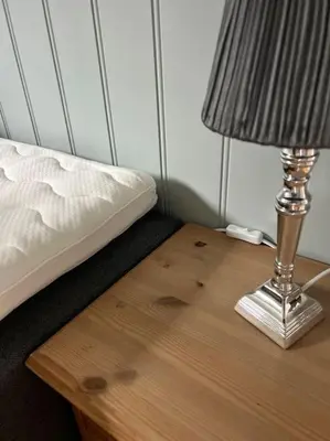 a lamp on a table next to a bed at Sokkel-leilighet med nærhet til sentrum og Hovden skiheis in Oppdal