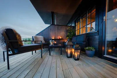 a deck with a table and a chair and lights at Storefjell Resort - Panorama apartments in Gol