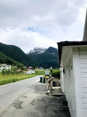 a building next to a road with mountains in the background at Flat in the center of Loen in Loen