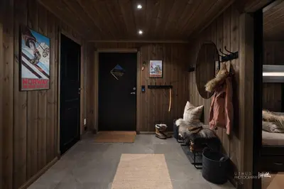 a hallway with wood paneled walls and a door at Ny og moderne hytte med sauna, jacuzzi og eget spillrom med biljard og dart Gratis elbillading og strøm inkludert i prisen in Flå