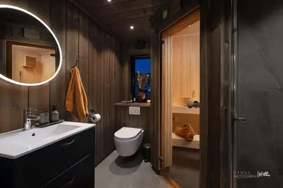 a bathroom with a sink and a toilet and a mirror at Ny og moderne hytte med sauna, jacuzzi og eget spillrom med biljard og dart Gratis elbillading og strøm inkludert i prisen in Flå