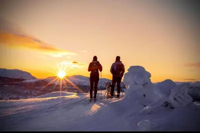 two people on skis standing on top of a mountain with the sunset at Ny og moderne hytte med sauna, jacuzzi og eget spillrom med biljard og dart Gratis elbillading og strøm inkludert i prisen in Flå