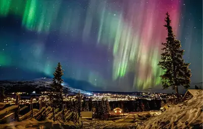 an aurora over a city with snow and trees at Awesome Home In Svingvoll With Sauna in Svingvoll