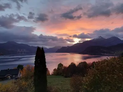 a sunset over a lake with a house and mountains at Norwegian Fjords Time Out in Stranda