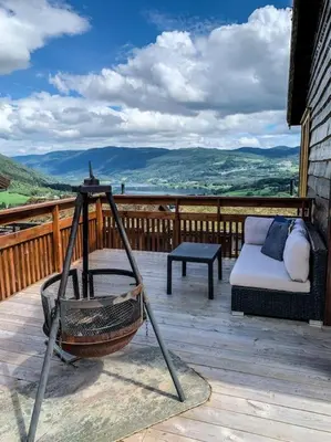 a porch with a swing and a couch on a deck at Spacious cabin with a fabulous view and a sauna in Skulestadmo