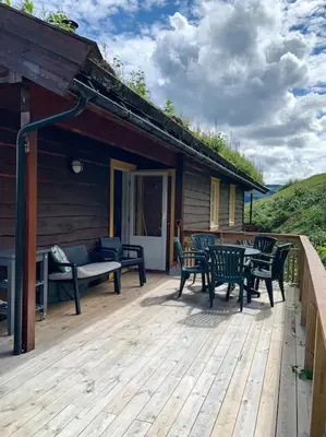 a deck with chairs and a table on a house at Spacious cabin with a fabulous view and a sauna in Skulestadmo