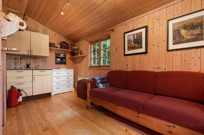 a living room with a red couch in a kitchen at Charming cabin retreat by the coast in Midsund in Midsund