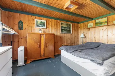 a bedroom with a bed and a wooden wall at Charming cabin retreat by the coast in Midsund in Midsund