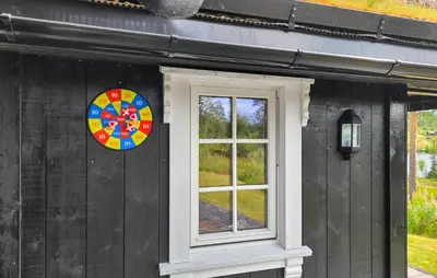 a wheel on the side of a black house with a window at Nice Home In Vinje With House Sea View in Trovatn