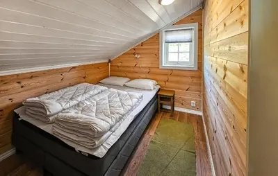 a bed in a room with a wooden wall at Nice Home In Vinje With House Sea View in Trovatn