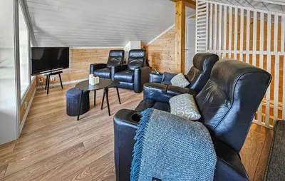 a living room with leather furniture and a flat screen tv at Nice Home In Vinje With House Sea View in Trovatn