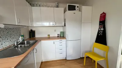 a kitchen with a white refrigerator and a yellow chair at Rustic Apartment in Bakklandet in Trondheim