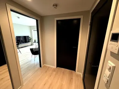 a hallway with a black door and a living room at Luxury Apartment in Bergen, 10min from City Centre in Bergen