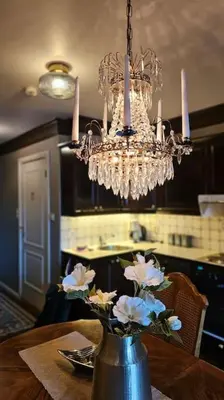 a vase with flowers on a table under a chandelier at Toppleilighet Dr Holms in Geilo