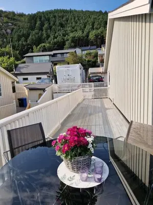 a glass table with a vase of flowers on a balcony at Hessahuset in Ålesund