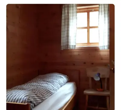 a bed in a wooden room with a window at Kårhus på småbruk in Lia