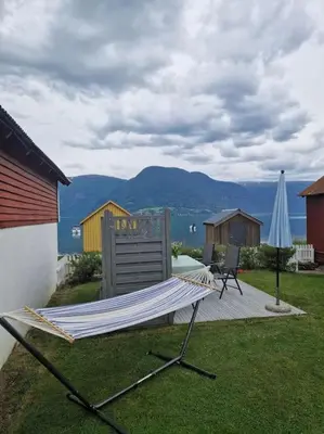 a hammock sitting on the grass next to a house at Feriehus ved fjorden i Solvorn in Luster