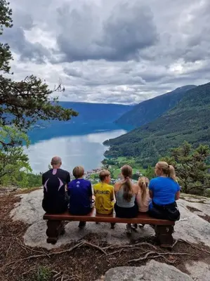 a group of people sitting on a bench overlooking a lake at Feriehus ved fjorden i Solvorn in Luster