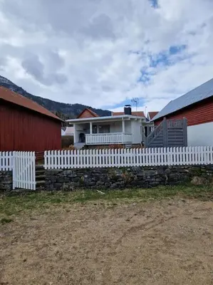 a white fence in front of a house at Feriehus ved fjorden i Solvorn in Luster