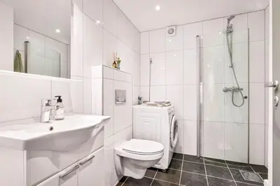 a white bathroom with a toilet sink and a shower at Leilighet i Bergens vakreste gate - Nydelig utsikt over innseilingen til Bergen! in Bergen