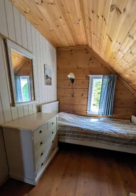a bedroom in a log cabin with a bed and two windows at Dønhaug Gjestegard in Uskedalen