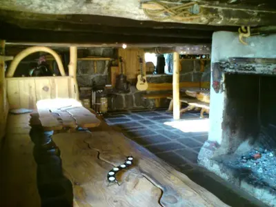 a living room with a fireplace and a wooden table at Dønhaug Gjestegard in Uskedalen