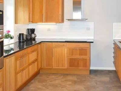 a kitchen with wooden cabinets and black counter tops at 9 person holiday home in Åram in Sandvik