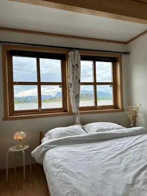 a bedroom with a white bed with two windows at Hus med panorama utsikt in Måløy