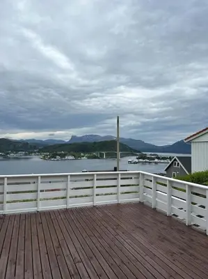 a wooden deck with a fence and a view of the water at Hus med panorama utsikt in Måløy