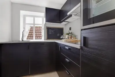 a kitchen with dark brown cabinets and a window at Very Central Beautiful Modern Apartment in Bergen