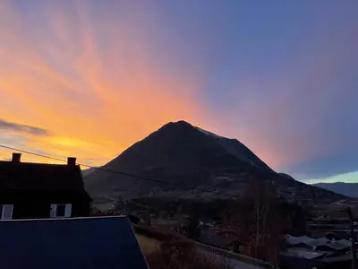 a mountain with a sunset in the background at Hyggelig og velutstyrt leilighet i Lom sentrum in Lom