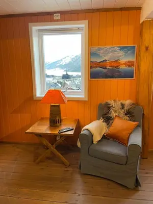 a room with a chair and a table with a lamp at Hyggelig og velutstyrt leilighet i Lom sentrum in Lom