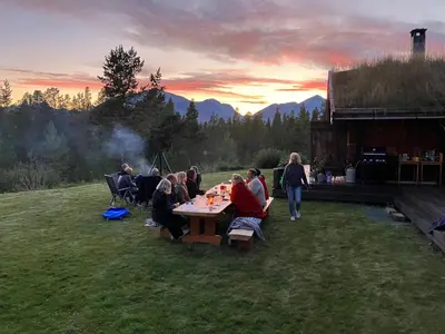 a group of people sitting at a table in the grass at Rondane - Øvre Nordli Sollia Friluftsliv in Atnfoss