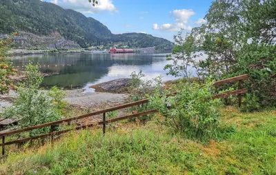 a fence next to a body of water with mountains at 2 Bedroom Nice Home In Skatval in Tilleraune