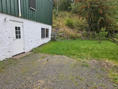 a building with a white door next to a yard at Leilighet Vingnes in Lillehammer