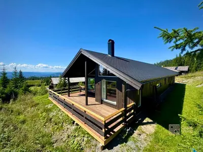 a cabin with a deck on top of a hill at New large cabin with sauna in Hafjell in Nordseter