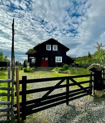 a black house with a fence in front of it at New large cabin with sauna in Hafjell in Nordseter