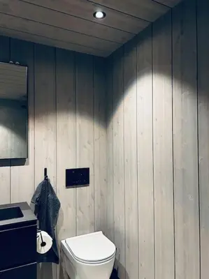 a bathroom with a toilet and a wooden wall at Eksklusiv hytte ved Fyri Resort - Utsikt in Hemsedal