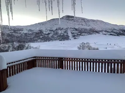 a snow covered balcony with a mountain in the background at Peaceful cabin retreat in the Norwegian mountains in Ulsteinvik
