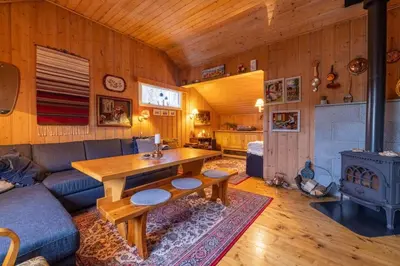 a living room with a couch and a table and a stove at Peaceful cabin retreat in the Norwegian mountains in Ulsteinvik