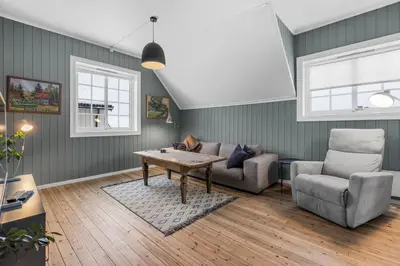a living room with a couch and a table and a chair at Sentral leilighet i klassisk hus! in Lillehammer