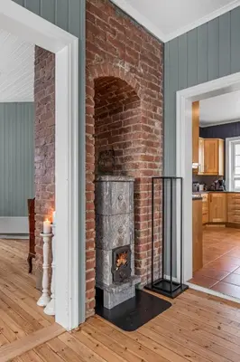 a brick fireplace in the middle of a living room at Sentral leilighet i klassisk hus! in Lillehammer