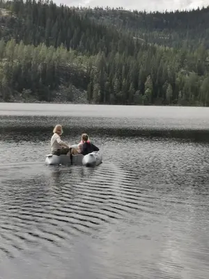 two people are sitting in a boat on a lake at Villa Ka Stor Elvdal in Koppang