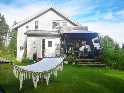 a house with an umbrella and a hammock in the yard at Villa Ka Stor Elvdal in Koppang