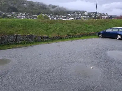 a blue car parked on the side of a road at Rom 6 sentralt i Sogndal in Sogndal